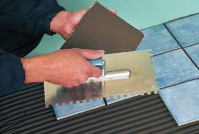 Une grande tuile est posée en appliquant un liant au sol et à l'arrière de la tuile Pour la pose de gros objets, du mortier ou de la colle est appliqué sur le sol et les carreaux